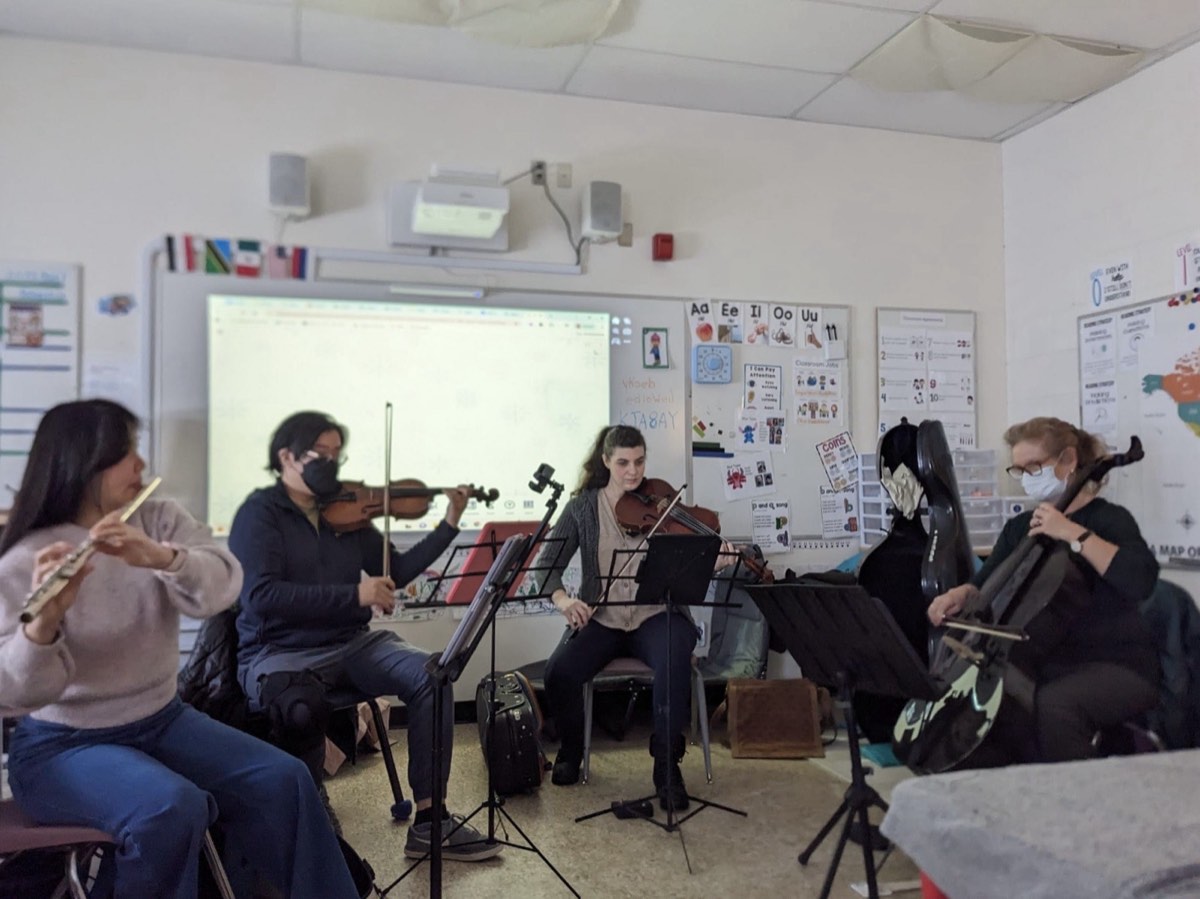 Musicians performing for students in a classroom setting